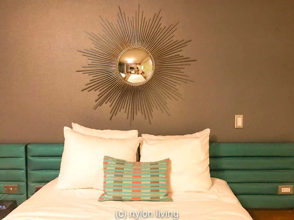 A starburst mirror above the bed pays homage to Mid century modern interior design