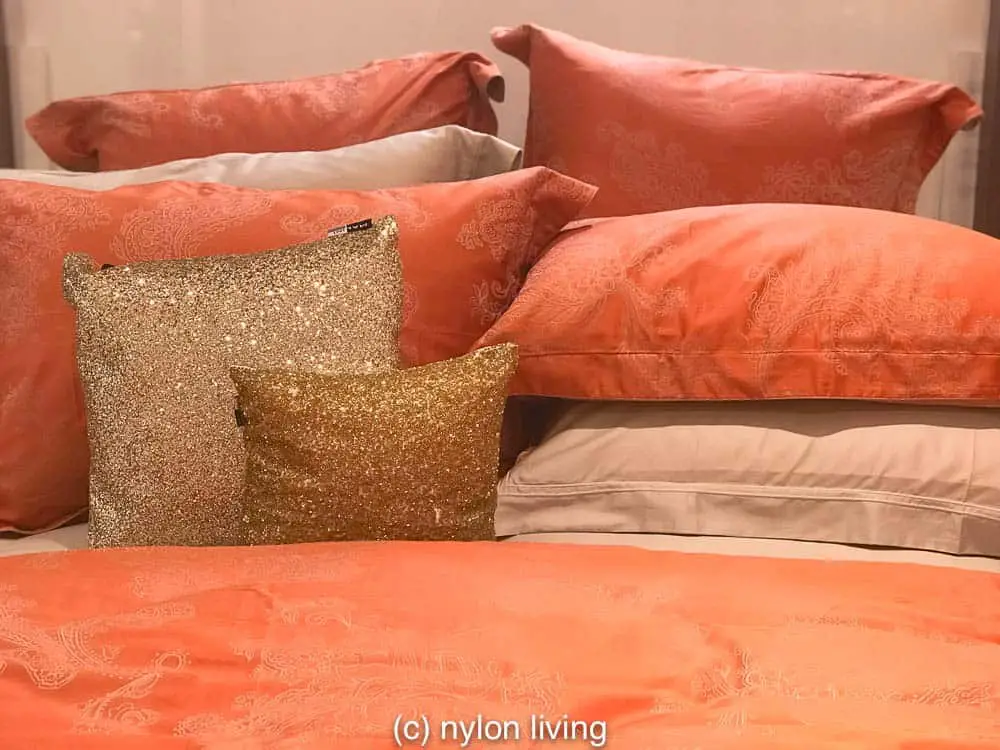 Coral coloured bedding with a gold accent pillow