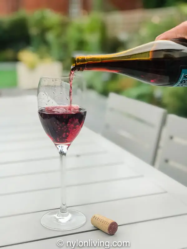pouring red wine into glass in garden